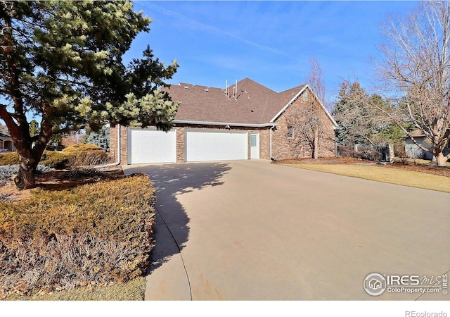 view of front facade with a garage, concrete driveway, brick siding, and a front lawn