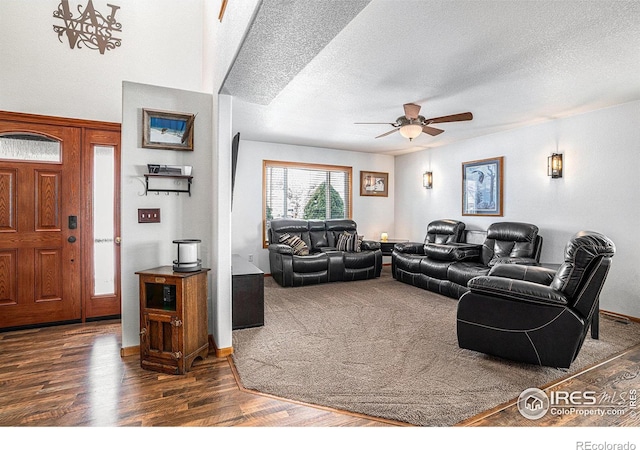 living room with ceiling fan, dark hardwood / wood-style floors, and a textured ceiling