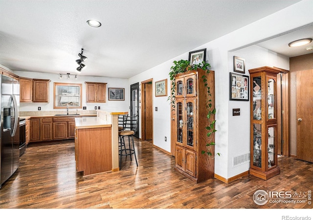 kitchen featuring sink, appliances with stainless steel finishes, dark hardwood / wood-style floors, a kitchen breakfast bar, and a kitchen island