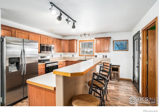 kitchen featuring appliances with stainless steel finishes, a center island, sink, and wood-type flooring