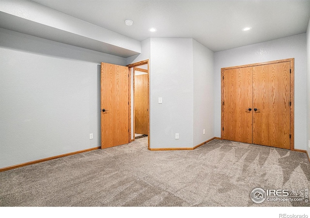 unfurnished bedroom with light colored carpet and a closet