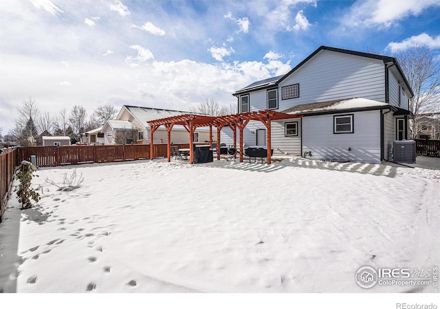 snow covered rear of property with a pergola and central AC