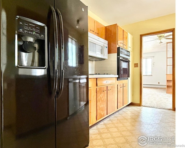 kitchen featuring a baseboard radiator, fridge with ice dispenser, and black oven