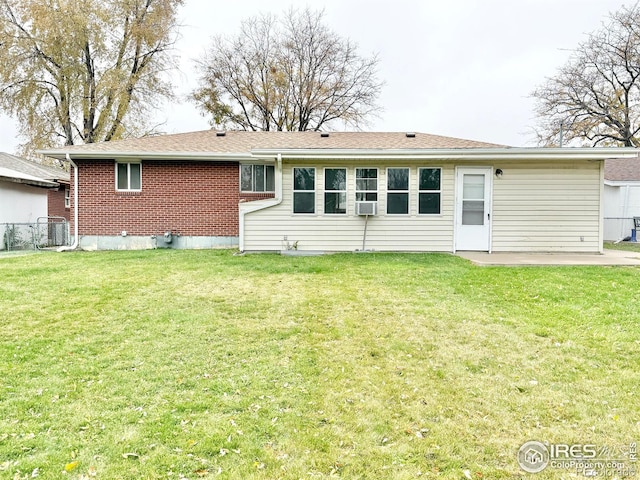 rear view of property with cooling unit, a patio area, and a lawn