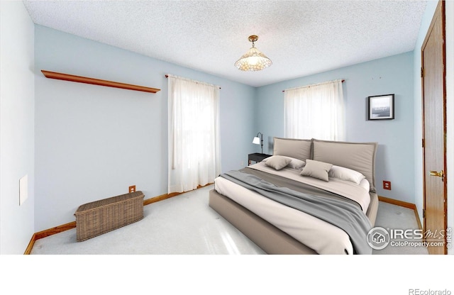 bedroom featuring multiple windows, light colored carpet, and a textured ceiling