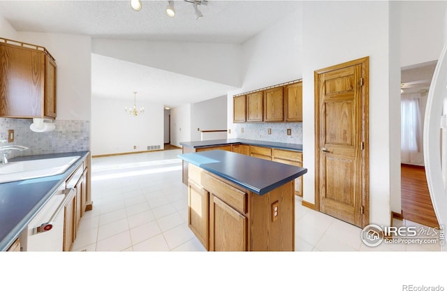 kitchen with sink, vaulted ceiling, light tile patterned floors, pendant lighting, and backsplash