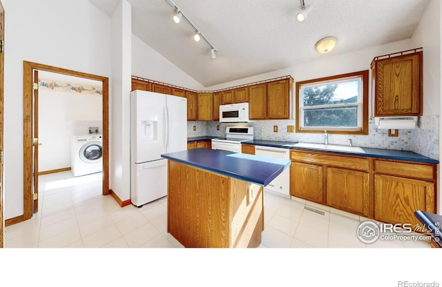 kitchen featuring washer / dryer, sink, lofted ceiling, a center island, and white appliances