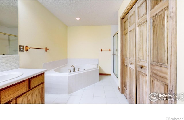 bathroom with vanity, shower with separate bathtub, tile patterned flooring, and a textured ceiling