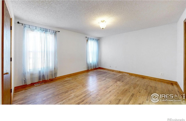 spare room with a textured ceiling and light wood-type flooring