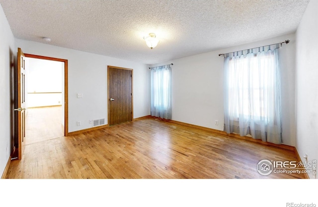 unfurnished bedroom featuring a closet, hardwood / wood-style floors, and a textured ceiling