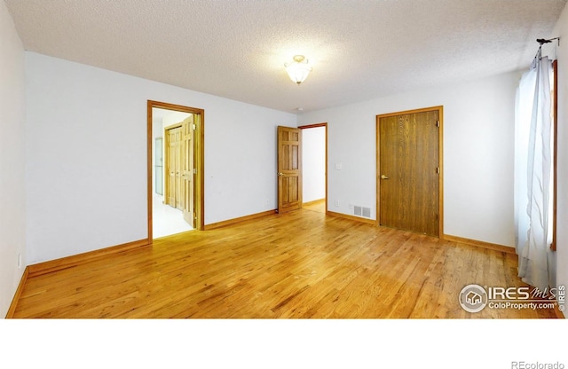 unfurnished bedroom with a textured ceiling and light wood-type flooring