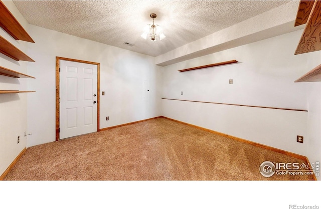 carpeted spare room featuring an inviting chandelier and a textured ceiling