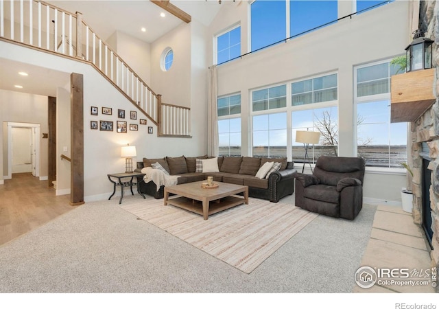 living room featuring a towering ceiling, a fireplace, light carpet, and a wealth of natural light