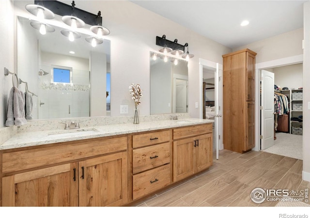 bathroom featuring a shower with door and vanity