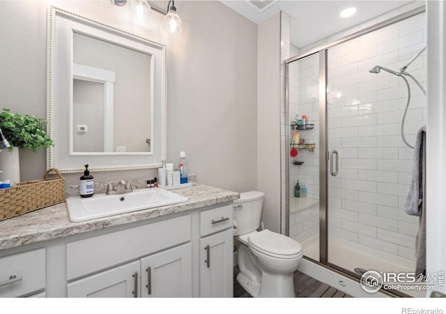 bathroom featuring vanity, a shower with door, and toilet