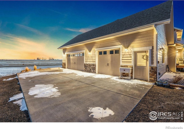 garage at dusk featuring a water view