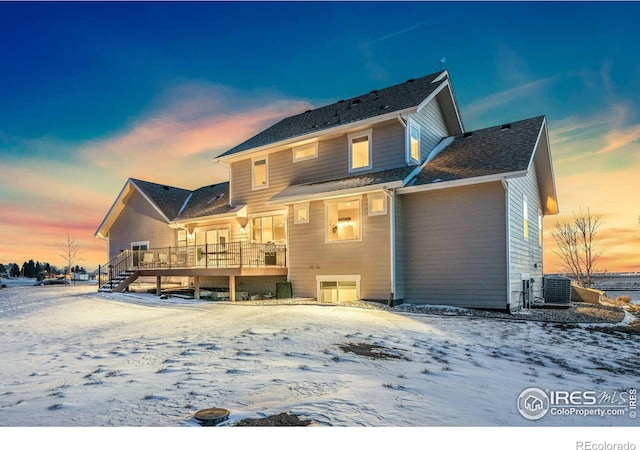 snow covered back of property featuring cooling unit and a deck