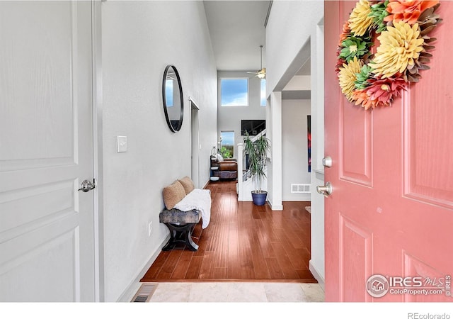 foyer entrance with ceiling fan and a high ceiling