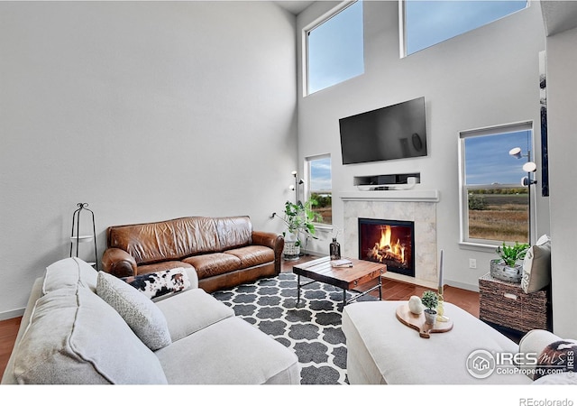 living room with hardwood / wood-style flooring, a fireplace, and a high ceiling