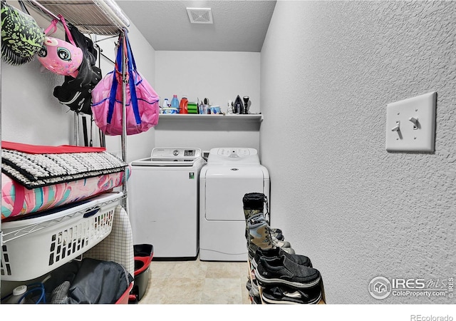 laundry area with washing machine and dryer and a textured ceiling