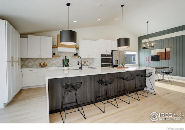 kitchen with stainless steel refrigerator with ice dispenser, white cabinetry, backsplash, and a spacious island