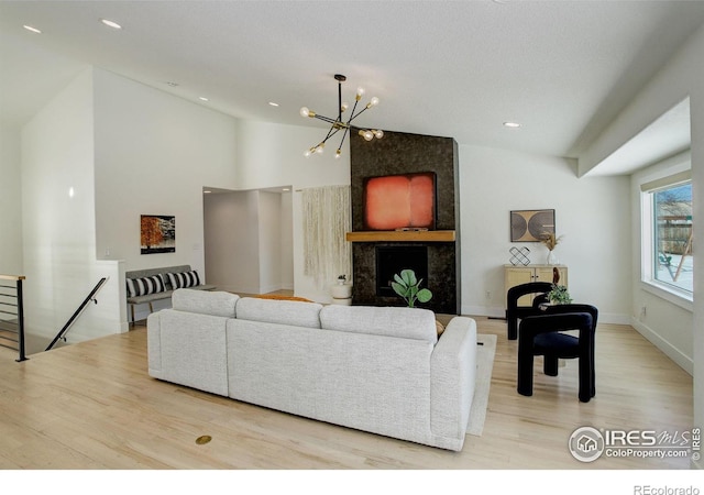 living room featuring an inviting chandelier, lofted ceiling, and light hardwood / wood-style flooring