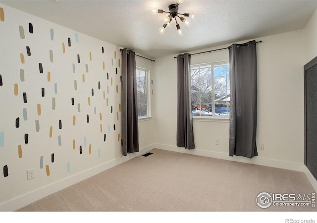 carpeted empty room with a textured ceiling