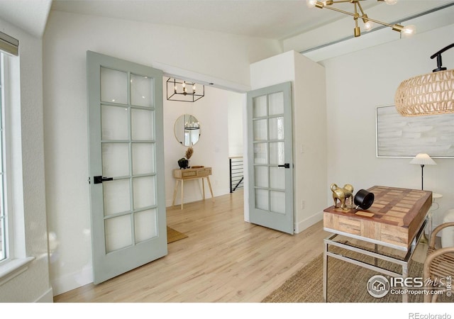 entryway with lofted ceiling, hardwood / wood-style floors, french doors, and a chandelier