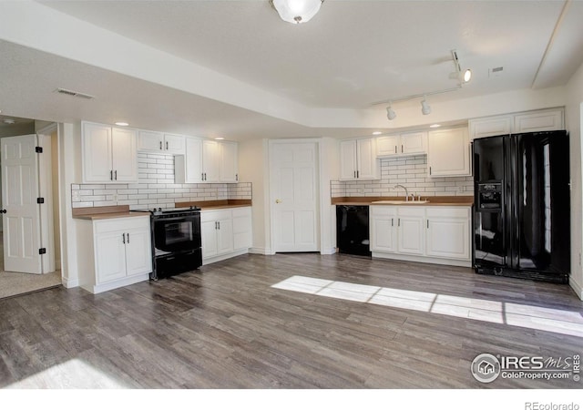 kitchen featuring white cabinetry, hardwood / wood-style flooring, tasteful backsplash, and black appliances