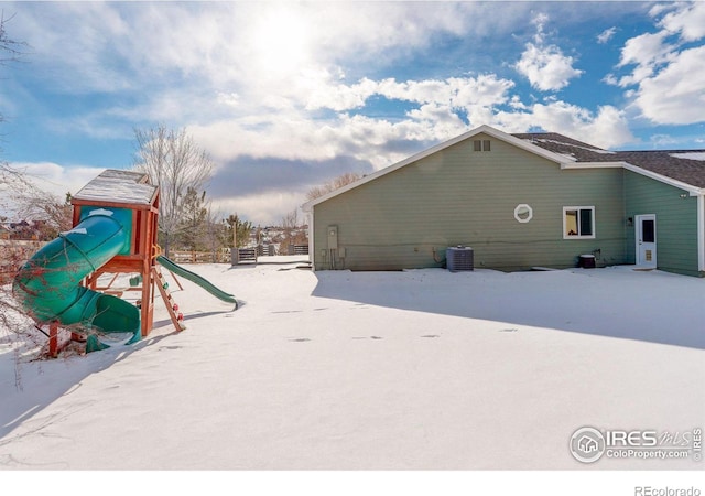 view of snow covered exterior featuring cooling unit and a playground