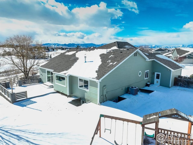 snow covered house featuring a mountain view and central air condition unit