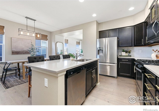 kitchen featuring sink, a breakfast bar area, hanging light fixtures, appliances with stainless steel finishes, and an island with sink