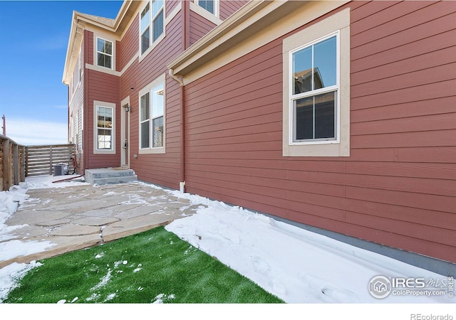 view of snowy exterior with central AC and a patio area