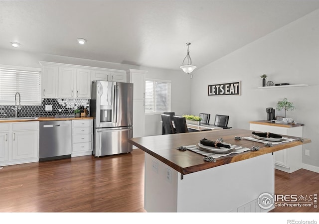 kitchen featuring stainless steel appliances, white cabinets, wood counters, and decorative light fixtures