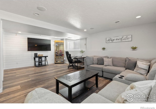 living room with dark hardwood / wood-style floors, a textured ceiling, and wood walls