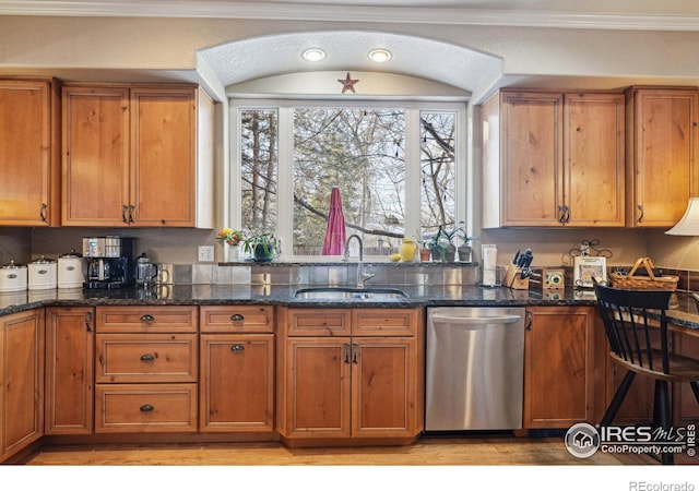 kitchen with ornamental molding, stainless steel dishwasher, a sink, and brown cabinets