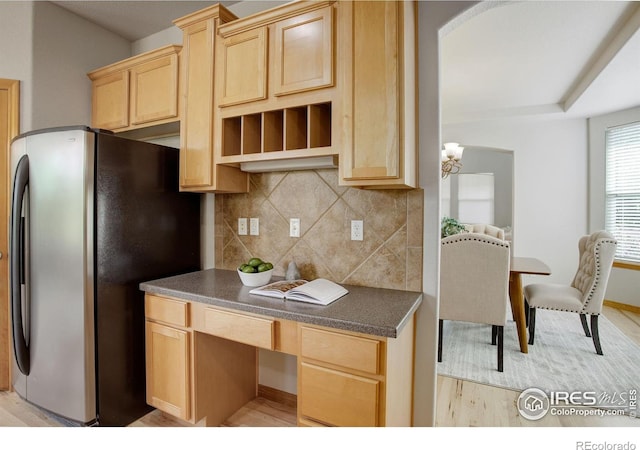 kitchen with decorative backsplash, light brown cabinetry, stainless steel refrigerator, and light hardwood / wood-style floors