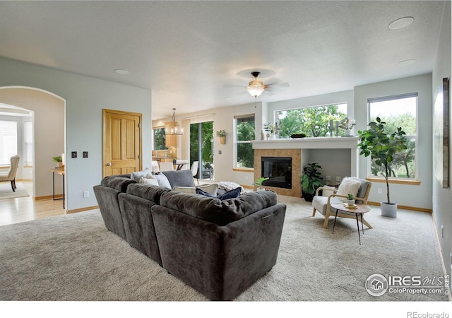 carpeted living room featuring a tile fireplace and ceiling fan