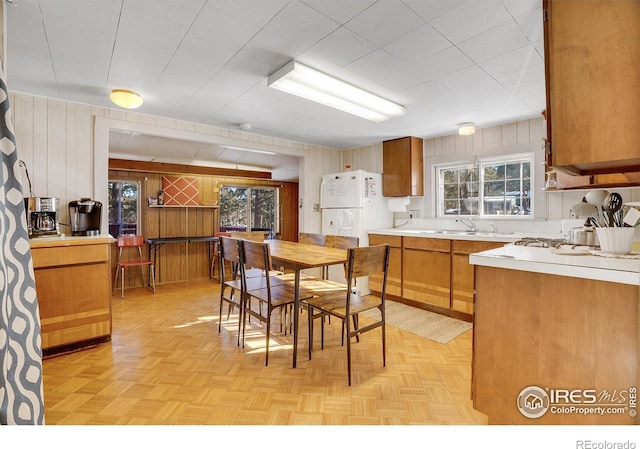 kitchen featuring sink, wood walls, light parquet flooring, and white refrigerator