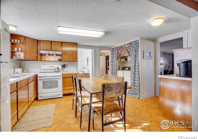 kitchen featuring sink, wooden walls, gas range gas stove, and light parquet floors