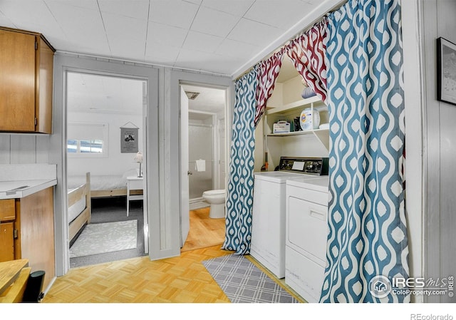 bathroom with parquet flooring, washer and dryer, and toilet