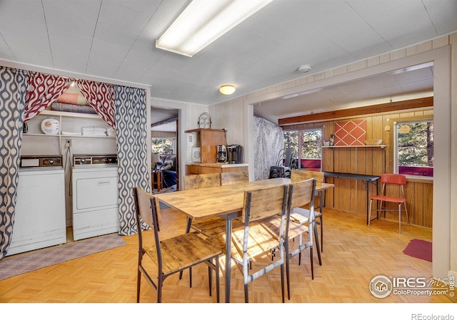 dining space featuring parquet floors, independent washer and dryer, and wooden walls