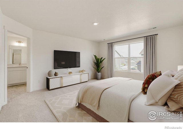 bedroom with ensuite bathroom and light colored carpet