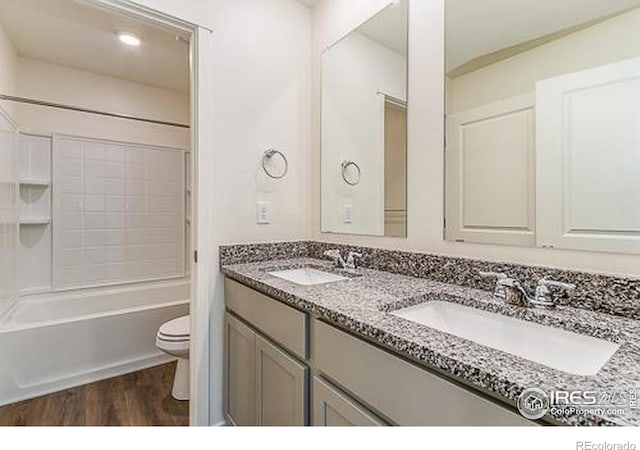 full bathroom with hardwood / wood-style flooring, shower / tub combination, vanity, and toilet