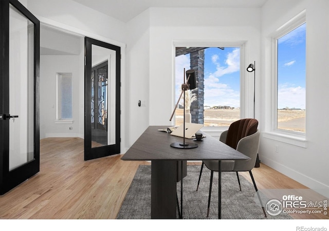 home office with light hardwood / wood-style floors and french doors