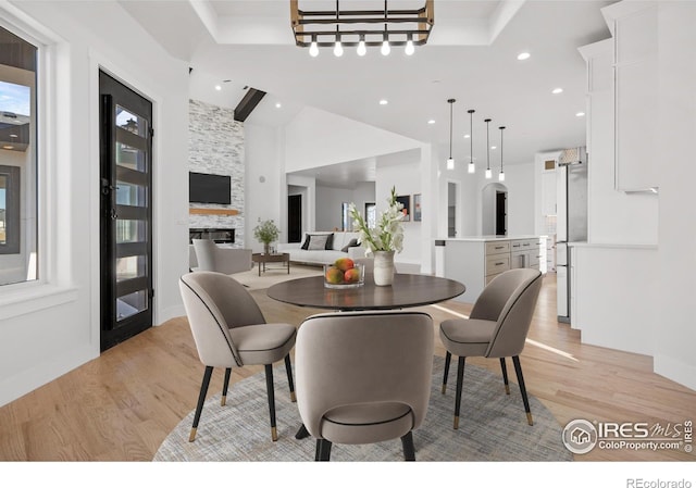 dining space featuring a stone fireplace, a wealth of natural light, and light hardwood / wood-style flooring