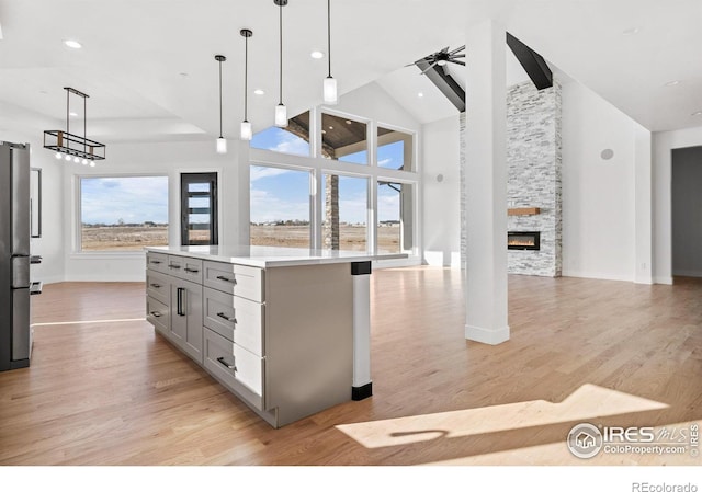 kitchen with gray cabinets, high vaulted ceiling, hanging light fixtures, a center island, and plenty of natural light