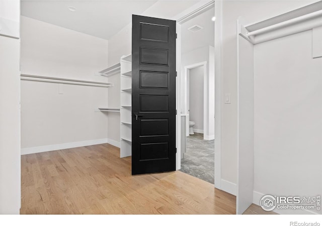 walk in closet with light hardwood / wood-style floors