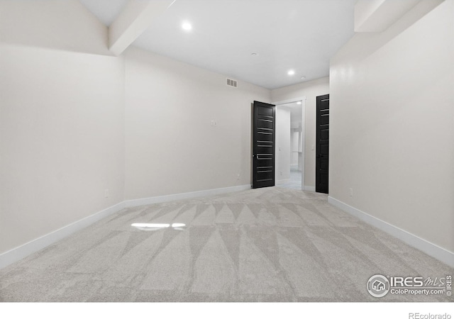 empty room with beam ceiling and light colored carpet