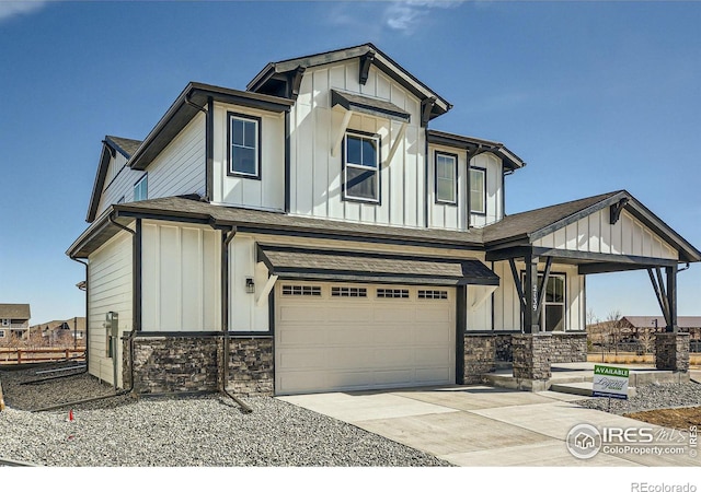 view of front of home with board and batten siding, a porch, driveway, stone siding, and an attached garage